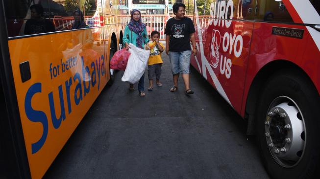 Warga membawa botol plastik melintas di antara Bus Suroboyo di Surabaya, Jawa Timur, Selasa (25/9). [ANTARA FOTO/Zabur Karuru]