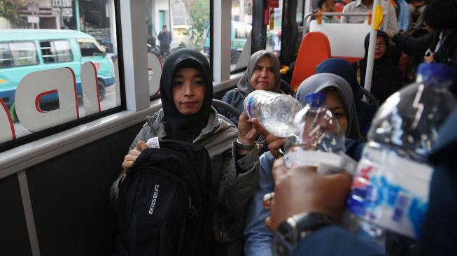 Warga membayar tiket dengan botol plastik bekas saat menumpang Bus Suroboyo di Surabaya, Jawa Timur, Selasa (25/9). [ANTARA FOTO/Zabur Karuru]