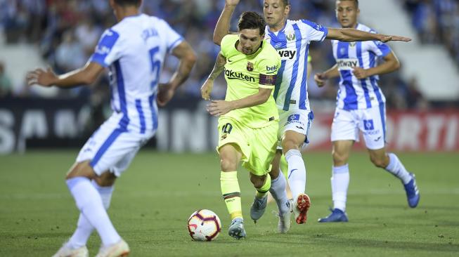 Lionel Messi berusaha melewati gelandang Leganes, selama pertandingan Leganes melawan  Barcelona di Estadio Municipal de Butarque,Spanyol, Rabu (26/9). [AFP/OSCAR DEL POZO] 
