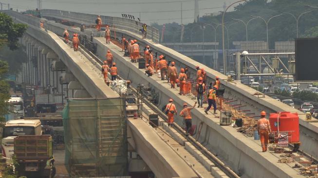 Sejumlah pekerja menyelesaikan pemasangan rel kereta ringan atau "Light Rail Transit" (LRT) rute Cibubur-Cawang di Jakarta,  Sabtu (29/9). [Suara.com/Muhaimin A Untung]