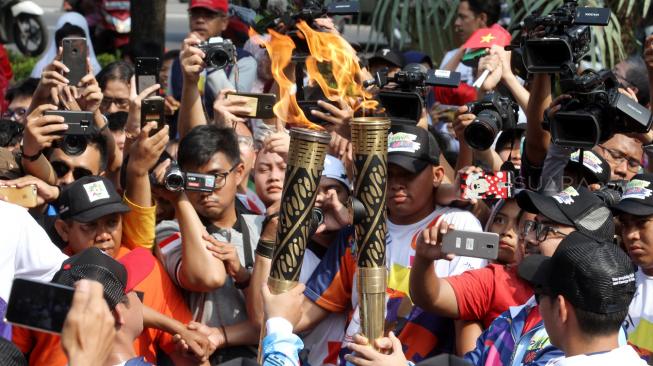 Suasana pawai obor Asian Para Games 2018 ketika melintas di kawasan Jalan Medan Merdeka Selatan, Jakarta, Minggu (30/9). [Suara.com/Oke Dwi Atmaja]