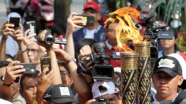 Suasana pawai obor Asian Para Games 2018 ketika melintas di kawasan Jalan Medan Merdeka Selatan, Jakarta, Minggu (30/9). [Suara.com/Oke Dwi Atmaja]