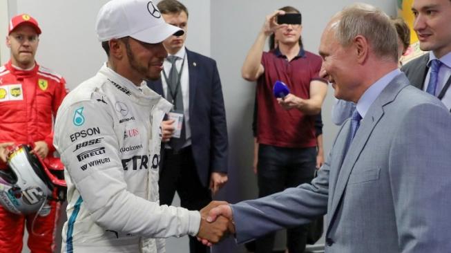 Pebalap Mercedes, Lewis Hamilton (kiri), bersalaman dengan Presiden Rusia Vladimir Putin usai memenangi balapan F1 GP Rusia di Sirkuit Sochi, Minggu (30/9/2018). [AFP/Mikhail Klimentyev]