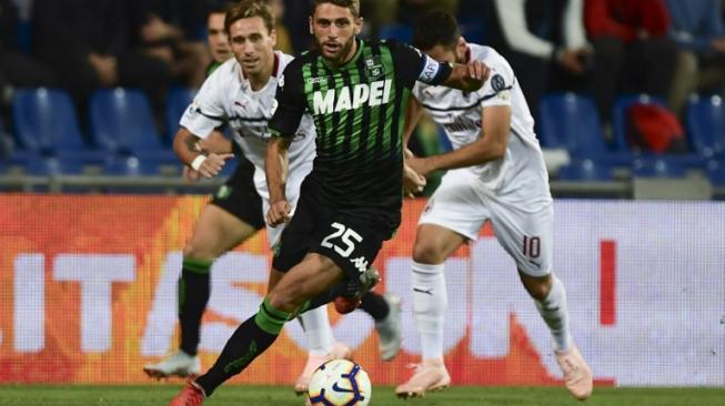 Penyerang Sassuolo, Domenico Berardi (tengah), melewati dua pemain AC Milan,  Lucas Biglia (kiri) dan Hakan Calhanoglu. Laga yang berlangsung di Stadion Mapei, Minggu (30/9/2018), ini berakhir dengan skor 4-1 untuk kemenangan AC Milan. [AFP/Miguel Medina]