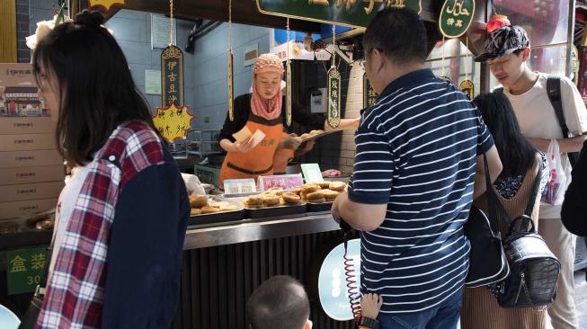 Seorang penjual melayani pembelinya yang menjual makanan halal di pasar Jalan Ben Yuan Men, kawasan komunitas muslim di Xi'an, Cina, Sabtu (29/9). [ANTARA FOTO/Hermanus Prihatna]
