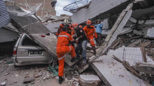 Petugas Basarnas membawa korban selamat gempa dan tsunami yang terjebak di dalam restoran Dunia Baru, Palu, Sulawesi Tengah, Minggu (30/9). [ANTARA FOTO/Muhammad Adimaja]