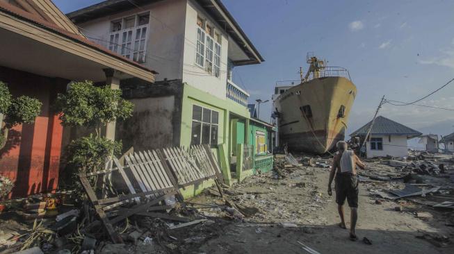 Warga melintas di depan Kapal Sabuk Nusantara 39 yang terdampar ke daratan di desa Wani, Pantai Barat Donggala, Sulawesi Tengah, Senin (1/10). [ANTARA FOTO/Muhammad Adimaja]