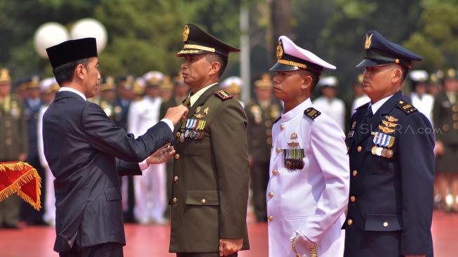 Presiden RI Jokowi memasang lencana kepada perwakilan penerima tanda kehormatan Republik Indonesia saat HUT TNI ke-73 di Markas Besar Tentara Nasional Indonesia, Cilangkap, Jakarta, Jumat (5/10). [Suara.com/Muhaimin A Untung]