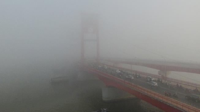 Sejumlah kendaraan melintas di atas jembatan Ampera yang tertutup kabut asap di Palembang, Sumatera Selatan, Jumat (5/10). [ANTARA FOTO/Nova Wahyudi]