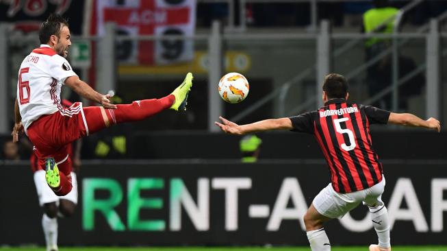 Pemain tengah Olympiakos Bebars Natcho melompat untuk mengambil bola di samping gelandang Milan Giacomo Bonaventura selama pertandingan sepak bola Grup F Liga Europa antara AC Milan melawan Olympiakos di stadion San Siro, Milan, Italia, Kamis (4/9). [AFP/Miguel MEDINA]