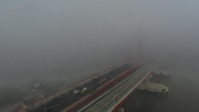 Sejumlah kendaraan melintas di atas jembatan Ampera yang tertutup kabut asap di Palembang, Sumatera Selatan, Jumat (5/10). [ANTARA FOTO/Nova Wahyudi]