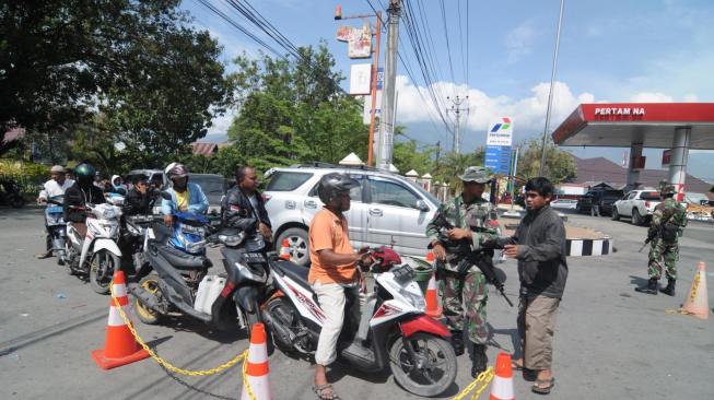 Anggota TNI berjaga di tengah antrean kendaraan di salah satu SPBU di Palu, Sulawesi Tengah, Sabtu (6/10). ANTARA FOTO/Basri Marzuki