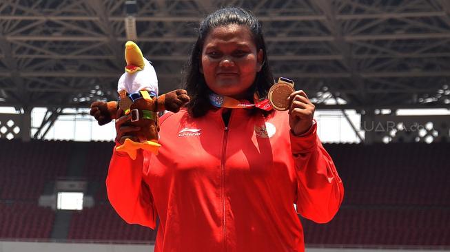 Atlet Indonesia Suparniyati memperlihatkan medali emas saat penyerahan medali atletik nomor tolak peluru F20 putri Asian Para Games 2018 di Stadion Utama GBK, Jakarta, Senin (8/10). [Suara.com/Muhaimin A Untung]