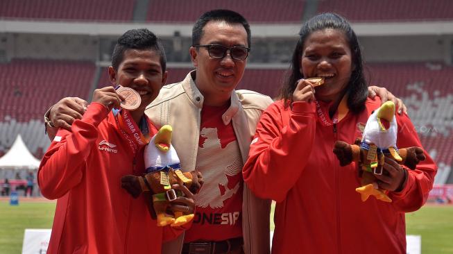 Menpora Imam Nahrawi (tengah) berfoto bersama atlet Indonesia Suparniyati (kanan) dan Tiwa usai penyerahan medali atletik nomor tolak peluru F20 putri Asian Para Games 2018 di Stadion Utama GBK, Jakarta, Senin (8/10). [Suara.com/Muhaimin A. Untung]