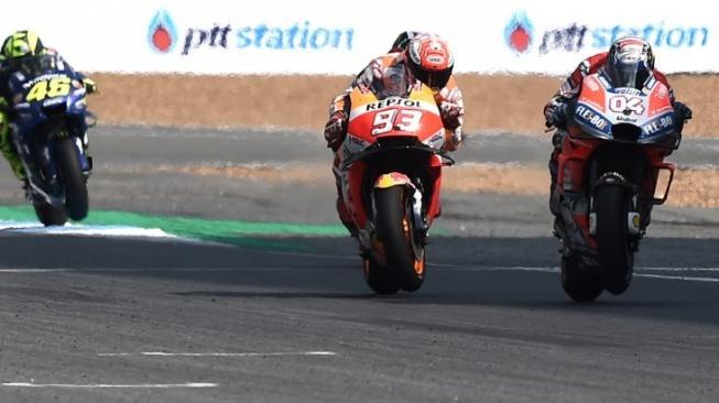 Pebalap Repsol Honda Marc Marquez (tengah) mencoba melewati pebalap Ducati Andrea Dovizioso (kanan) di MotoGP Thailand di Buriram International Circuit. LILLIAN SUWANRUMPHA / AFP