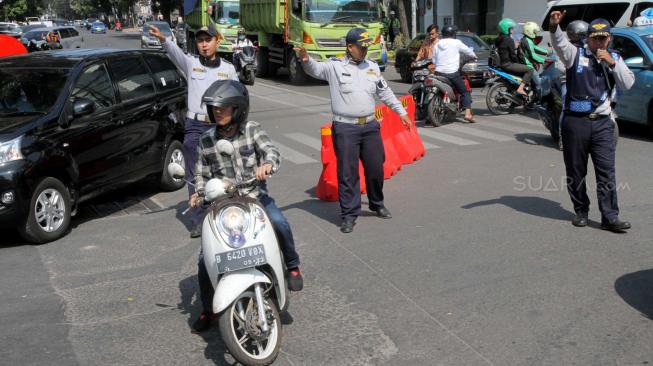 Sejumlah Petugas Dishub melakukan sosialisasi uji Coba Sistem satu arah Jalan KH Wahid Hasyim, Jakarta Pusat, Senin (8/10). [Suara.com/Fakhri Hermansyah]