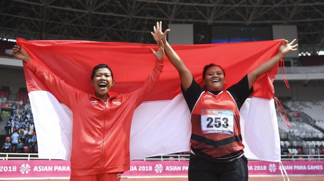 Atlet Indonesia Suparniyati (kanan) dan Tiwa meluapkan kegembiraan seusai bertanding pada babak final para atletik nomor tolak peluru F20 putri Asian Para Games 2018 di Stadion Utama GBK, Jakarta, Senin (8/10). ANTARA FOTO/Dhemas Reviyanto