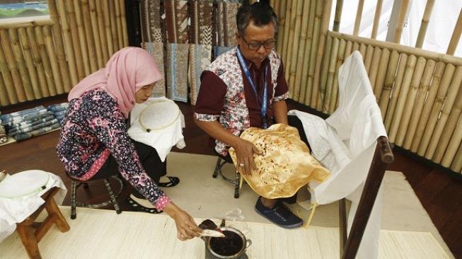 Pengrajin batik, Jumiaty (kiri) dan Sugiyarto (kanan) merupakan salah satu UMKM binaan BNI yang ikut berpartisipasi dalam Indonesia Pavilion. Mereka mengenalkan batik tulis Lasem kepada seluruh delegasi yang hadir di Pertemuan Tahunan International Monetary Fund (IMF) - World Bank (WB) 2018 yang diselenggarakan di Nusa Dua Bali pada 8-14 Oktober 2018. (Foto: Dok. Indonesia Pavilion)