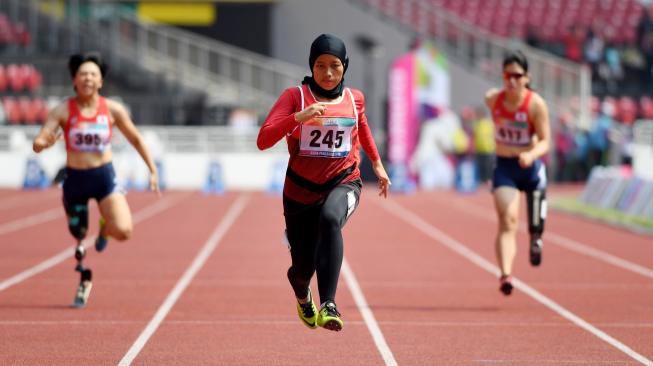 Sprinter Indonesia Karisma Evi Tiarani (tengah) memacu kecepatan saat berlaga dalam nomor 100 meter putri T42 dan T63 Asian Para Games 2018 di Stadion Utama Gelora Bung Karno, Jakarta, Rabu (10/10). [ANTARA FOTO/Akbar Nugroho Gumay]
