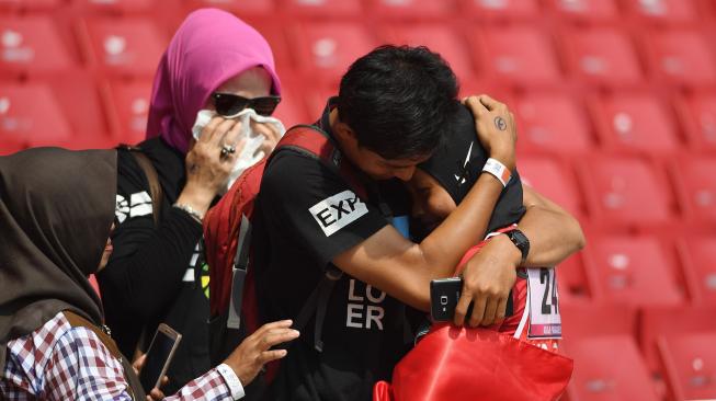 Sprinter Indonesia Karisma Evi Tiarani (kanan) dipeluk keluarganya usai finis terdepan dalam nomor 100 meter putri T42 dan T63 Asian Para Games 2018 di Stadion Utama Gelora Bung Karno, Jakarta, Rabu (10/10). [ANTARA FOTO/Akbar Nugroho Gumay]