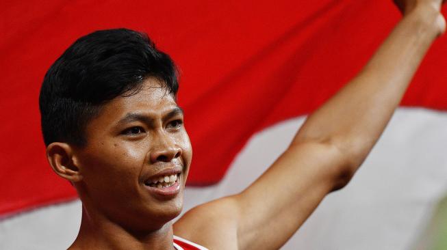 Sprinter Indonesia Sapto Yogo Purnomo mengibaskan bendera Merah-Putih usai menjuarai final 100 meter putra T37 Asian Para Games di Stadion Utama Gelora Bung Karno, Senayan, Jakarta, Selasa (9/10). [ANTARA FOTO/Sigid Kurniawan]
