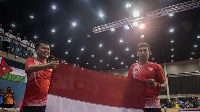 Petenis meja Indonesia David Jacobs (kanan) dan Komet Akbar (kiri) mengibarkan bendera Merah Putih usai bertanding melawan petenis meja Korea Selatan Shin Seung Weon/Jung Sukyoun dalam babak final para tenis meja TT 10 ganda putra Asian Para Games 2018 di Jakarta, Rabu (10/10). [ANTARA FOTO/Galih Pradipta]