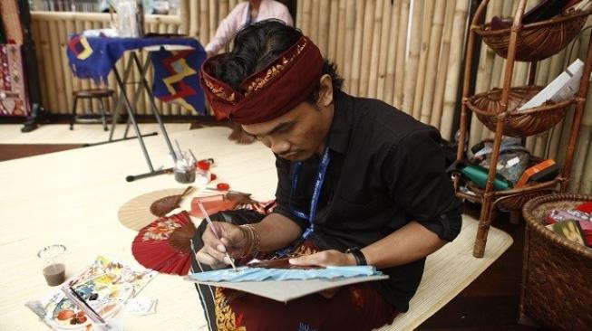 Seorang pengrajin sedang melukis kipas lipat khas Bali. (Foto: Dok. Indonesia Pavilion)