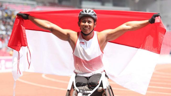 Pebalap kursi roda Indonesia, Jaenal Aripin, melakukan selebrasi usai meraih medali perak pada Asian Para Games cabang atletik nomor balap kursi roda 200 meter T 54 di Stadion Utama Gelora Bung Karno,  Jakarta, Jumat (12/10). [Suara.com/Muhaimin A Untung] 