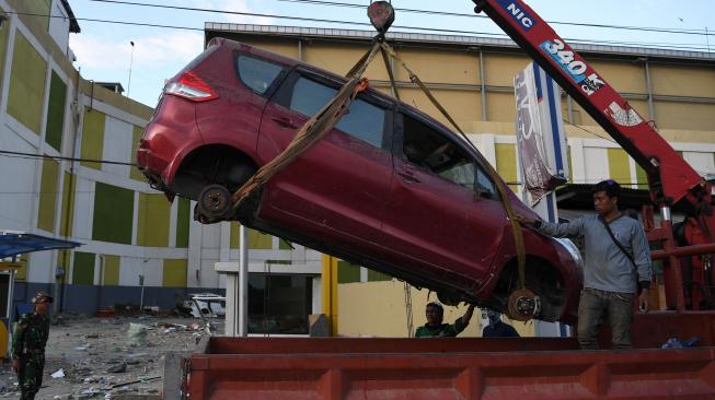 Petugas mengevakuasi mobil yang rusak akibat gempa dan tsunami di Lere, Palu, Sulawesi Tengah, Rabu (10/10) [ANTARA FOTO/Wahyu Putro A].