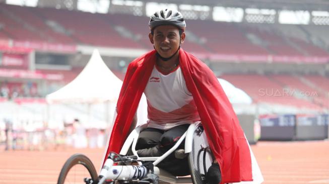 Pebalap kursi roda Indonesia, Jaenal Aripin, melakukan selebrasi usai meraih medali perak pada Asian Para Games cabang atletik nomor balap kursi roda 200 meter T 54 di SUGBK, Jakarta, Jumat (12/10). [Suara.com/Muhaimin A Untung] 