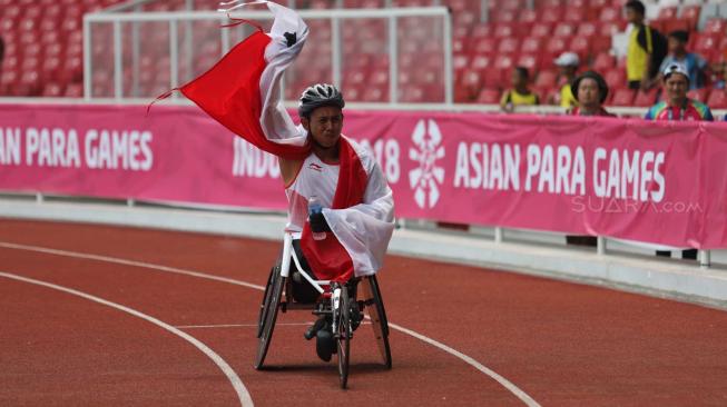 Pebalap kursi roda Indonesia, Jaenal Aripin, melakukan selebrasi usai meraih medali perak pada Asian Para Games cabang atletik nomor balap kursi roda 200 meter T 54 , di Stadion Utama Gelora Bung Karno, Jakarta, Jumat (12/10). [Suara.com/Muhaimin A Untung] 