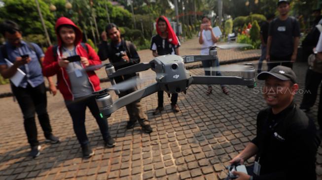 Peserta mencoba menerbangkan Kamera drone Mavic 2 zoom di Taman Cattleya, Jakarta Barat, Jumat (12/10).  
[Suara.com/Muhaimin A Untung]  
