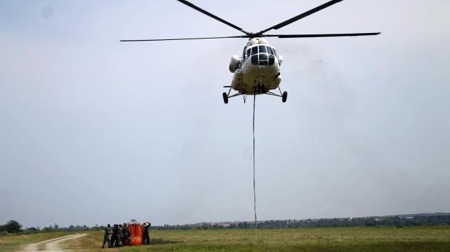 Helikopter Badan Nasional Penanggulangan Bencana (BNPB) bersiap membawa cairan desinfektan melalui udara dengan metode water bombing di titik lokasi gempa likuifaksi, Balaroa dan Sigi, Sulawesi Tengah, Kamis (18/10). [ANTARA FOTO/Darwin Fatir]