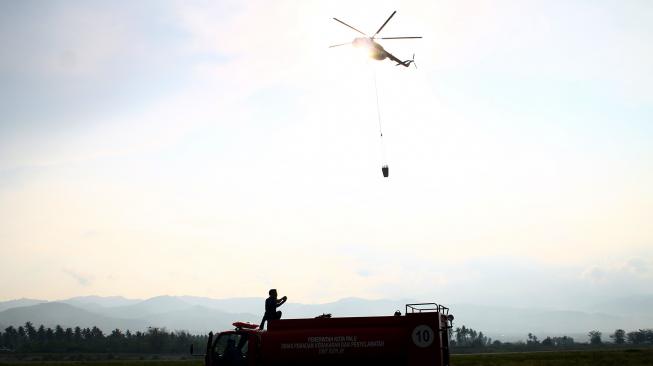 Helikopter Badan Nasional Penanggulangan Bencana (BNPB) bersiap membawa cairan desinfektan melalui udara dengan metode water bombing di titik lokasi gempa likuifaksi, Balaroa dan Sigi, Sulawesi Tengah, Kamis (18/10). [ANTARA FOTO/Darwin Fatir]