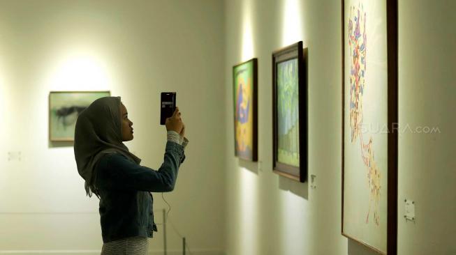 Pengunjung mengamati sejumlah karya saat pameran seni yang bertajuk 'Menyigi Masa' di Galeri Nasional, Jakarta, Kamis (18/10). [Suara.com/Muhaimin A Untung]