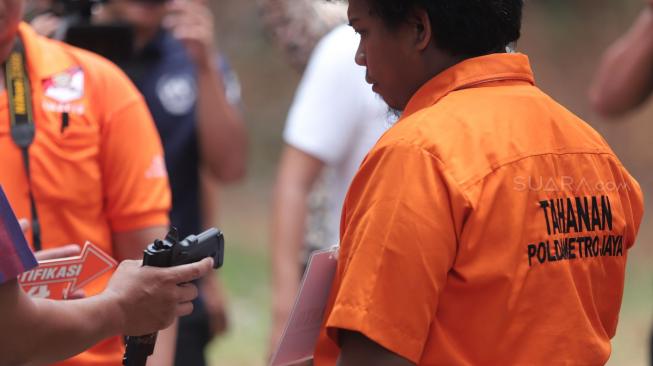 Tersangka mencontohkan menembak saat melakukan gelar rekonstruksi terkait kasus peluru nyasar gedung DPR RI di Lapangan Tembak, Senayan, Jakarta, Jumat (19/10). [Suara.com/Muhaimin A Untung]