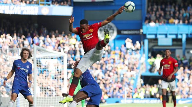 Striker Manchester United Anthony Martial melompat untuk mengambil bola dengan bek Chelsea Antonio Rudiger selama pertandingan sepak bola Liga Premier Inggris antara Chelsea melawan Manchester United di Stadion Stamford Bridge, London, Inggris, Sabtu (20/10). [AFP/Glyn KIRK] 