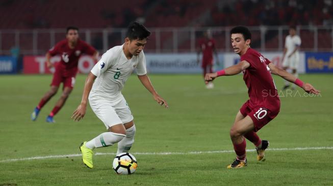 Pesepak bola Timnas Indonesia Witan Sulaeman mencoba melewati pesepak bola Qatar Khaled Mohammed dalam penyisihan Grup A Piala Asia U-19 di Stadion Utama Gelora Bung Karno, Jakarta, Minggu (21/10). [Suara.com/Muhaimin A Untung]