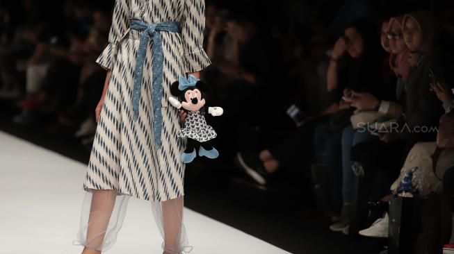 Model mengenakan pakaian rancangan desainer Didiet Maulana dari IKAT Indonesia saat peragaan busana Disney's Mickey Mouse: The True Orginal di Jakarta Fashion Week 2019 di Senayan City, Jakarta, Senin (22/10). [Suara.com/Muhaimin A Untung]