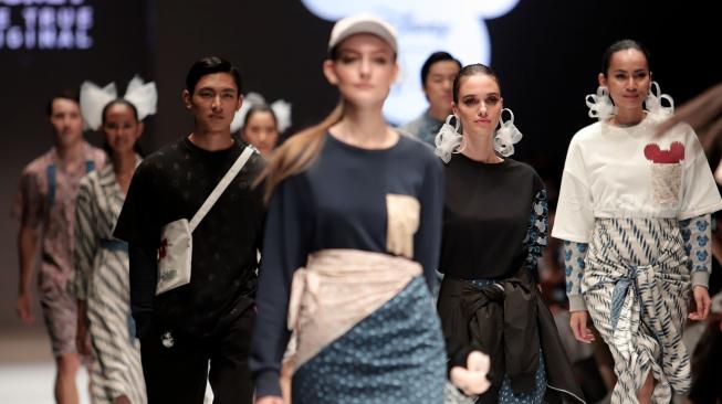 Sejumlah model mengenakan pakaian rancangan desainer Didiet Maulana dari IKAT Indonesia saat peragaan busana Disney's Mickey Mouse: The True Orginal di Jakarta Fashion Week 2019 di Senayan City, Jakarta, Senin (22/10). [Suara.com/Muhaimin A Untung]