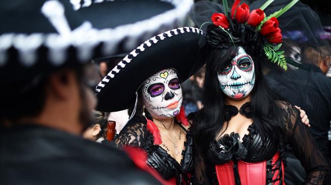 Seorang wanita menghias dirinya seperti seorang yang telah mati di perayaan Day of the Dead 2018 di kota Meksiko, Minggu (21/10). [Afp Photo/Rodrigo Arangua]