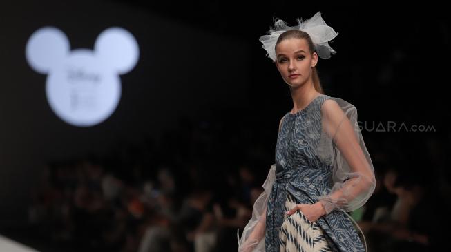 Model mengenakan pakaian rancangan desainer Didiet Maulana dari IKAT Indonesia saat peragaan busana Disney's Mickey Mouse: The True Orginal di Jakarta Fashion Week 2019 di Senayan City, Jakarta, Senin (22/10). [Suara.com/Muhaimin A Untung]