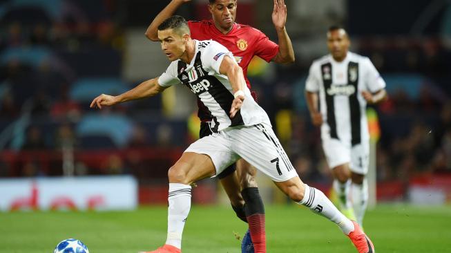 Striker Juventus Cristiano Ronaldo melewati striker Manchester United Marcus Rashford selama pertandingan sepak bola grup H Liga Champions antara Manchester United melawan Juventus di Old Trafford, Manchester, Inggris, Selasa (23/10).  [AFP/Oli SCARFF]