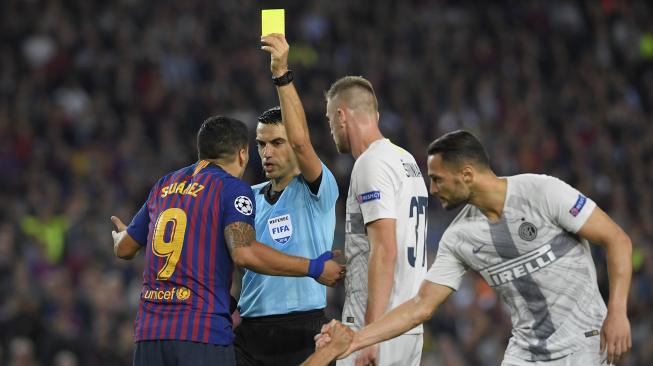 Wasit Ovidiu Hategan memberikan kartu kuning kepada pemain depan Barcelona Luis Suarez selama pertandingan Grup B Liga Champions  Barcelona melawan Inter Milan di Stadion Camp Nou, Barcelona, Spanyol, Rabu (24/10).  (AFP/LLUIS GENE)
