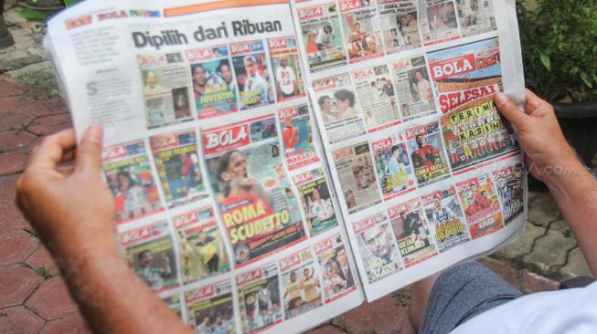 Warga membaca Tabloid Olahraga Bola edisi terakhir di Duren Sawit, Jakarta, Jumat (26/10). (Suara.com Fakhri Hermansyah)