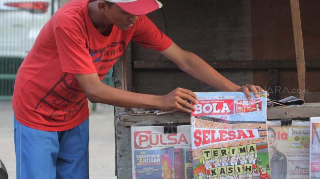 Loper koran saat menyusun Tabloid Olahraga Bola edisi terakhir yang akan dijual di kawasan Duren Sawit, Jakarta, Jumat (26/10). (Suara.com Fakhri Hermansyah)