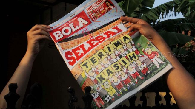 Loper koran saat mengirimkan Tabloid Olahraga Bola edisi terakhir kepada pembaca di kawasan Duren Sawit, Jakarta, Jumat (26/10). (Suara.com Fakhri Hermansyah)