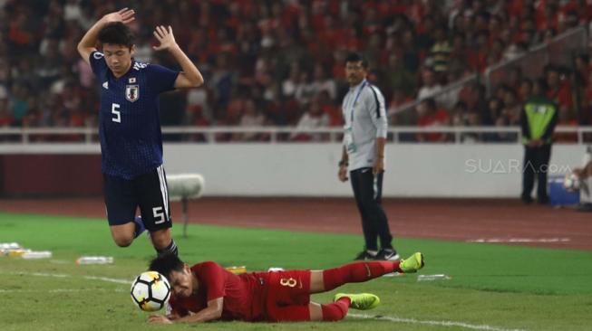 Pesepak bola Indonesia Witan Sulaiman terjatuh saat berebut bola dengan pesepak bola Jepang Yukinari SUgawara dalam babak perempat final Piala Asia U-19 di Stadion Utama Gelora Bung Karno, Senayan, Jakarta, Minggu (28/10/2018). [Suara.com/Muhaimin A Untung]