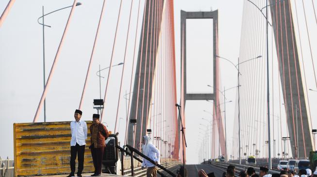 
Presiden Joko Widodo (kiri) didampingi Ibu Negara Iriana Joko Widodo (kanan) menaiki truk saat akan meresmikan pembebasan tarif tol Jembatan Suramadu di Surabaya, Jawa Timur, Sabtu (27/10).  [ANTARA FOTO/Zabur Karuru]