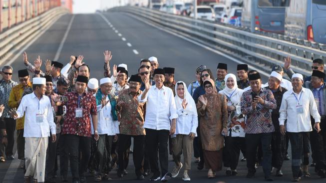 Presiden Joko Widodo (ketiga kanan) didampingi Ibu Negara Iriana Joko Widodo (ketiga kiri), Menteri PUPR Basuki Hadimuljono (kiri), Sekretaris Kabinet Pramono Anung (kanan) dan Gubernur Jawa Timur Soekarwo (keempat kanan) serta pejabat setempat dan para ulama berada diatas truk saat meresmikan pembebasan tarif tol Jembatan Suramadu di Surabaya, Jawa Timur, Sabtu (27/10). [ANTARA FOTO/Zabur Karuru]